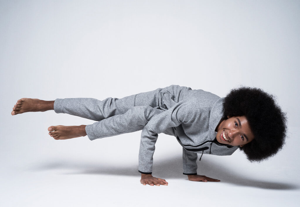 Tabey Atkins in yoga pose wearing a grey sweatsuit. 